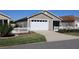 Single-car garage with white door, well-manicured lawn, and landscaping at 1805 Endsley Ct, The Villages, FL 32162