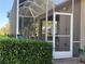 View of the screened porch with access door and surrounding green hedge providing privacy at 1970 Farmington Ct, Clermont, FL 34711