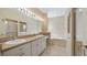 Bright bathroom featuring double sink vanity, soaking tub, tiled floor, and large mirror with Hollywood lights at 20740 Queen Alexandra Dr, Leesburg, FL 34748