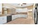 Bright kitchen features white cabinets, tiled floor, stainless steel dishwasher, and modern countertops at 20740 Queen Alexandra Dr, Leesburg, FL 34748