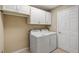 Laundry room features a washer, dryer, storage cabinets, and a tiled floor at 20740 Queen Alexandra Dr, Leesburg, FL 34748