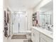 Bright bathroom featuring a glass shower, double sink vanity, and linen shelving for storage at 212 Taft Dr, Davenport, FL 33837