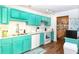 Bright kitchen featuring teal cabinets, white appliances, and a stainless-steel sink at 2225 Cypress Ct # 2C, Tavares, FL 32778