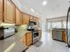 Bright kitchen features wood cabinets, mosaic backsplash, stainless steel appliances, and connects to dining area at 24002 Robinwood St, Leesburg, FL 34748