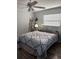 Well-lit bedroom with ceiling fan, gray bedding, white headboard, dark floors and shelving at 2416 Briarwood Ln, Eustis, FL 32726