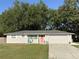 Charming single-story home with a well-manicured lawn and a welcoming coral-colored front door at 2416 Briarwood Ln, Eustis, FL 32726