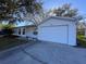 Front exterior featuring an attached garage and well maintained lawn at 25527 Oak Aly, Leesburg, FL 34748