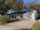 A daytime front exterior shot showing a wide driveway and partial shade at 25527 Oak Aly, Leesburg, FL 34748