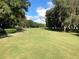 Expansive golf course featuring lush green fairways bordered by mature trees under a blue sky at 25527 Oak Aly, Leesburg, FL 34748