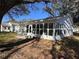 Rear of home featuring an enclosed sunroom with lots of windows, back patio, and manicured lawn at 25527 Oak Aly, Leesburg, FL 34748