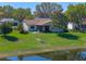 Well-maintained backyard with a small patio area, mature tree, and a glimpse of a pond beyond the green lawn at 26636 Evert St, Leesburg, FL 34748
