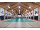 Indoor tennis court featuring wood ceiling, stage, flags, and a green and beige playing surface at 26636 Evert St, Leesburg, FL 34748