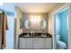 Bathroom with double vanity, marble countertops, decorative mirrors, and walk-in shower at 314 Olanta Dr, The Villages, FL 32162