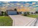 A long driveway featuring decorative concrete work leads up to the front of the home, surrounded by meticulously maintained landscaping at 314 Olanta Dr, The Villages, FL 32162