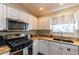 Kitchen with stainless steel appliances, granite countertops, white cabinets, and natural light at 314 Olanta Dr, The Villages, FL 32162