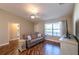 Comfortable living room featuring wood floors, a ceiling fan, and a large window, adjacent to a hallway with a bathroom at 314 Olanta Dr, The Villages, FL 32162