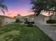 Charming single-story home features a well-manicured lawn and inviting entrance at sunset at 3337 Ashbrook Pl, The Villages, FL 32162
