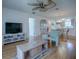 Cozy living area with sleek TV, hardwood floors, and a ceiling fan with seamless flow into the kitchen at 3337 Ashbrook Pl, The Villages, FL 32162