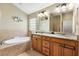 Bathroom featuring a bathtub, dual sinks, and wood cabinets at 3373 Melbourne Ln, The Villages, FL 32163