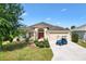 Inviting single-story home with a well-manicured lawn, mature trees, and a golf cart parked in the driveway at 3373 Melbourne Ln, The Villages, FL 32163