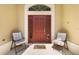 Welcoming front porch featuring a red front door with glass sidelights and comfortable seating at 3373 Melbourne Ln, The Villages, FL 32163