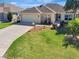 Well-maintained single-story home with a two-car garage, lush lawn, and landscaping at 3405 Rabbit Run Path, The Villages, FL 32163