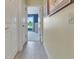 Hallway with wood-look tile leads to sunlit bedroom with open doorway and white walls at 3405 Rabbit Run Path, The Villages, FL 32163