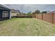 A beautiful fenced-in backyard with grass, mature trees, and green bushes provides a peaceful outdoor retreat at 345 Alcove Dr, Groveland, FL 34736