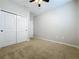 An empty bedroom with neutral walls, carpet, ceiling fan and double door closet at 345 Alcove Dr, Groveland, FL 34736