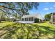 Scenic backyard view with a sunroom extension, a patio, mature trees, and lush landscaping at 3909 River Crest Cir, Leesburg, FL 34748