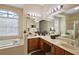 Bright bathroom featuring double sinks, wooden cabinets, and a separate soaking tub at 4818 Sawgrass Lake Cir, Leesburg, FL 34748