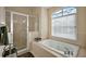 Elegant bathroom showcasing a tiled shower, soaking tub, and a large arched window at 4818 Sawgrass Lake Cir, Leesburg, FL 34748