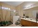Bathroom with a glass shower, light wood vanity, and tropical decor at 4818 Sawgrass Lake Cir, Leesburg, FL 34748