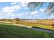 Scenic view of a lush golf course with a pond in the distance under a sunny, cloudy sky at 4818 Sawgrass Lake Cir, Leesburg, FL 34748