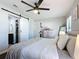 Spacious bedroom showcasing a sliding barn door, a ceiling fan, and a comfortable bed with soft pillows at 4857 Se 137Th Pl, Summerfield, FL 34491