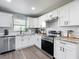 Updated kitchen featuring white cabinets, stainless steel appliances, and modern gray floors at 4857 Se 137Th Pl, Summerfield, FL 34491