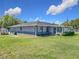 Back exterior of the home showcasing a large yard, screened in patio, and partial fencing at 4857 Se 137Th Pl, Summerfield, FL 34491