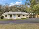 Charming single-story home with a blue front door, well-manicured lawn, and convenient covered parking at 502 Lake Gracie Dr, Eustis, FL 32726