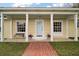 Inviting front porch featuring a brick walkway, bench seating, columns and decorative flowerpots at 502 Lake Gracie Dr, Eustis, FL 32726