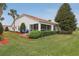 Charming home with a neatly landscaped backyard, screened lanai, and two blue chairs on a brick patio at 5056 Harbour Dr, Oxford, FL 34484