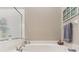 Corner bathtub with tiled surround, handheld showerhead and window to the garden at 5056 Harbour Dr, Oxford, FL 34484