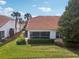 Charming home exterior with a red tile roof, screened lanai, and lush landscaping for outdoor enjoyment at 5056 Harbour Dr, Oxford, FL 34484
