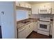 Bright kitchen with white cabinets, microwave, and view into living room space with sink, stove and dishwasher at 5214 Via Hacienda Cir # A308, Orlando, FL 32839