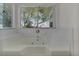 Oversized soaking tub with jets and tiled surround with window view at 5402 Rosewall Cir, Leesburg, FL 34748
