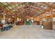 Spacious barn interior featuring wooden beams, concrete floors, and ample storage at 6813 S Fork Ranch Dr, Clermont, FL 34714