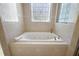 Close up of a soaking tub with jets and a decorative window, surrounded by tile at 6813 S Fork Ranch Dr, Clermont, FL 34714