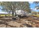 A white travel trailer sits in a shaded location on this acreage at 6813 S Fork Ranch Dr, Clermont, FL 34714