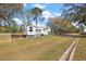 RV featuring a pull-out patio and awning with a manicured lawn and wooden perimeter at 6813 S Fork Ranch Dr, Clermont, FL 34714