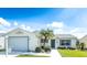 Charming home exterior with manicured lawn, a palm tree, and a two-car garage at 773 Artesia Ave, The Villages, FL 32162