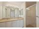 Bathroom featuring dual sinks, granite countertop, white cabinets, and tiled walk-in shower at 776 Alcott Ave, The Villages, FL 32162